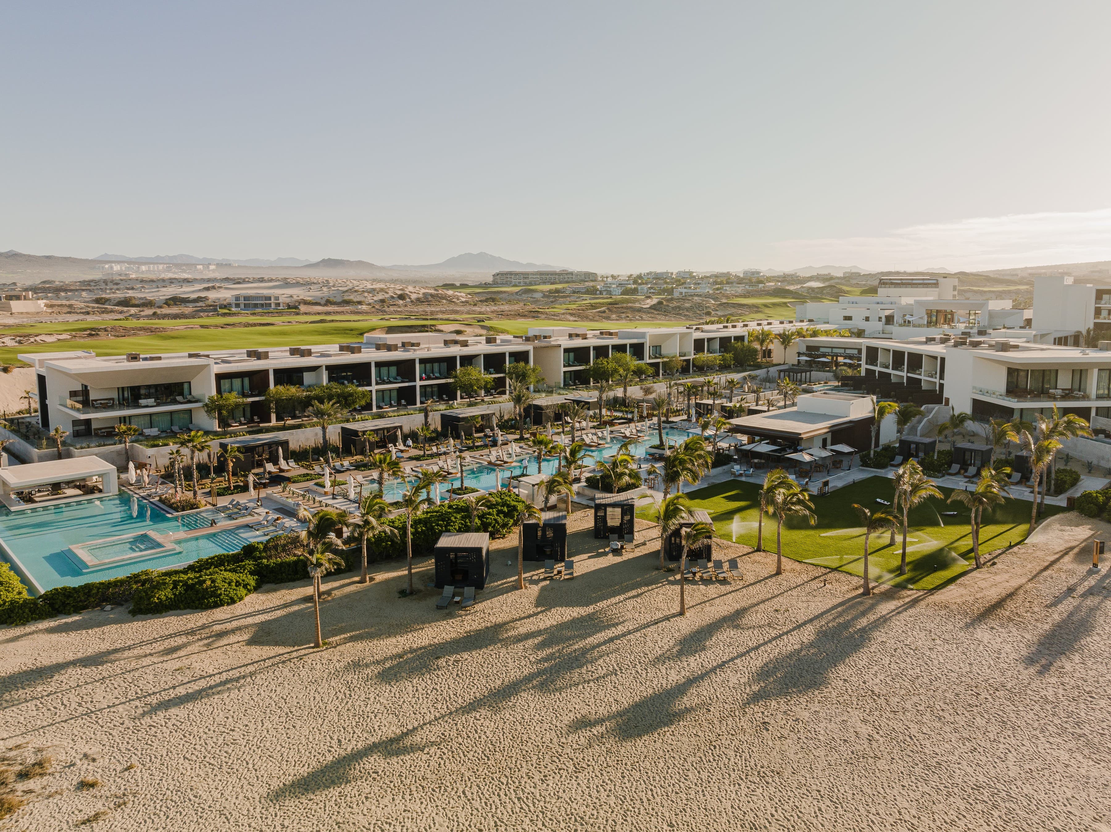 Aerial view of Nobu Hotel Los Cabos above the beach, golf course behind